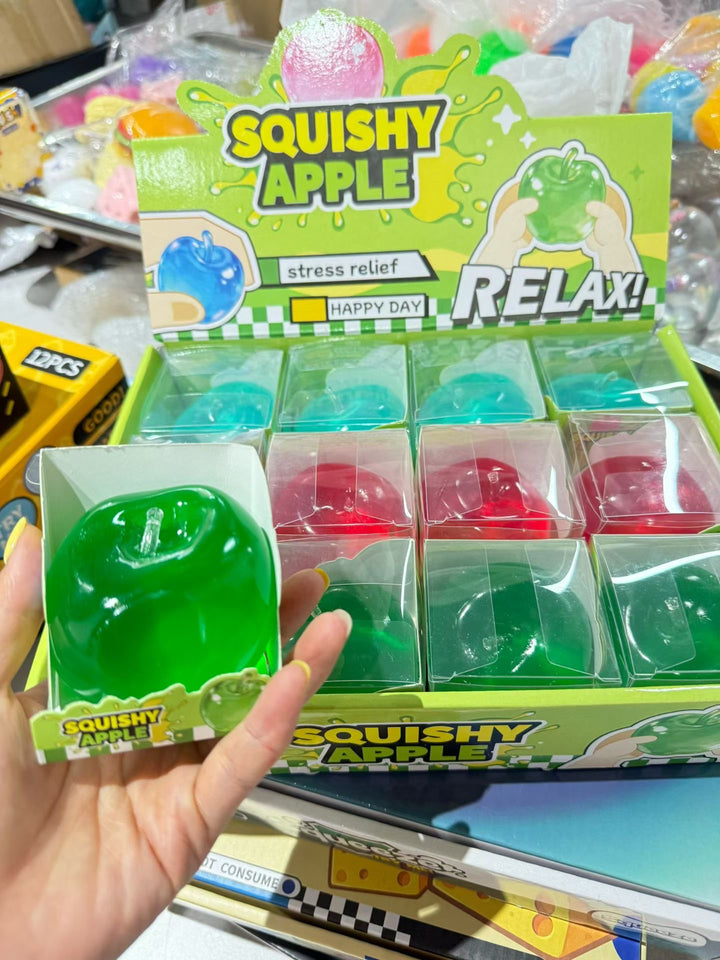 Glossy green apple squishy fidget toy in a clear retail box