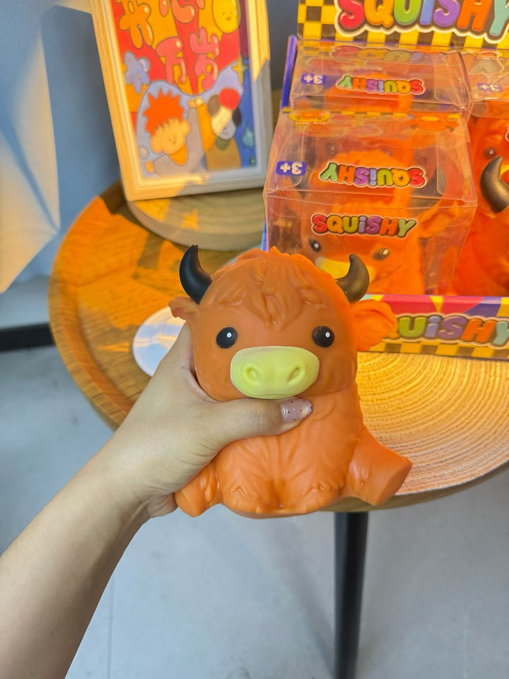 Orange Highland cow slow-rising squishy being squeezed by hand